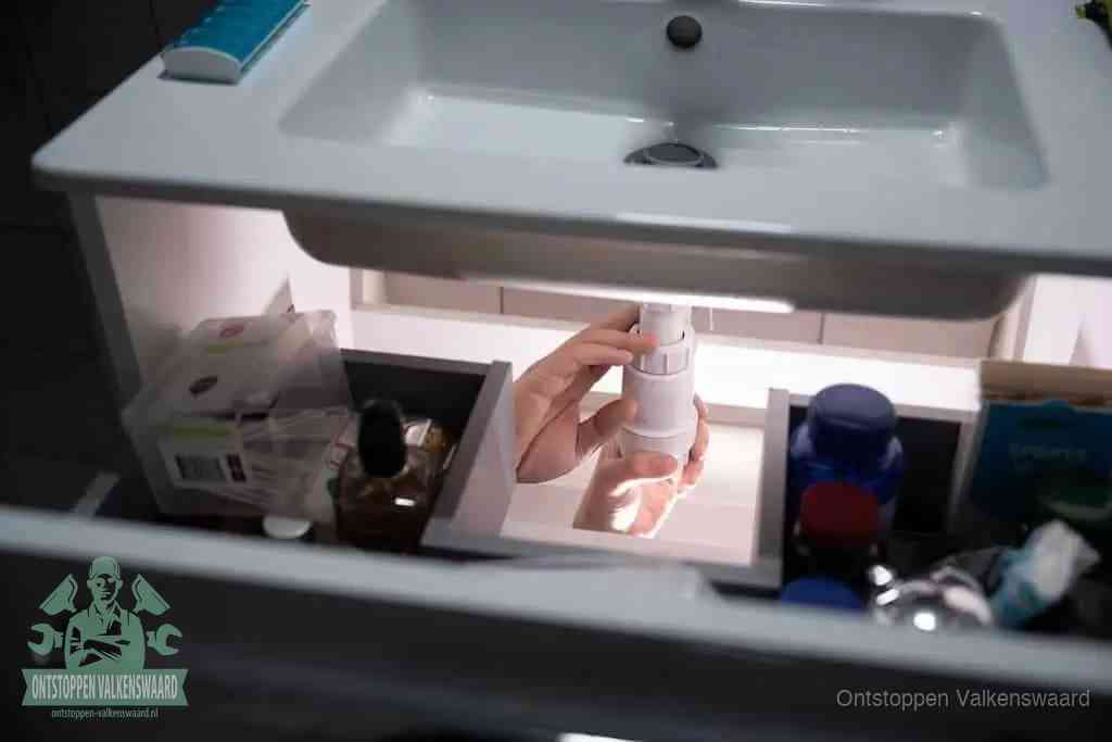 Een pompfles met zeep boven een wastafel, de heet water en afwasmiddel-methode om een vetprop in de afvoer los te maken in Valkenswaard