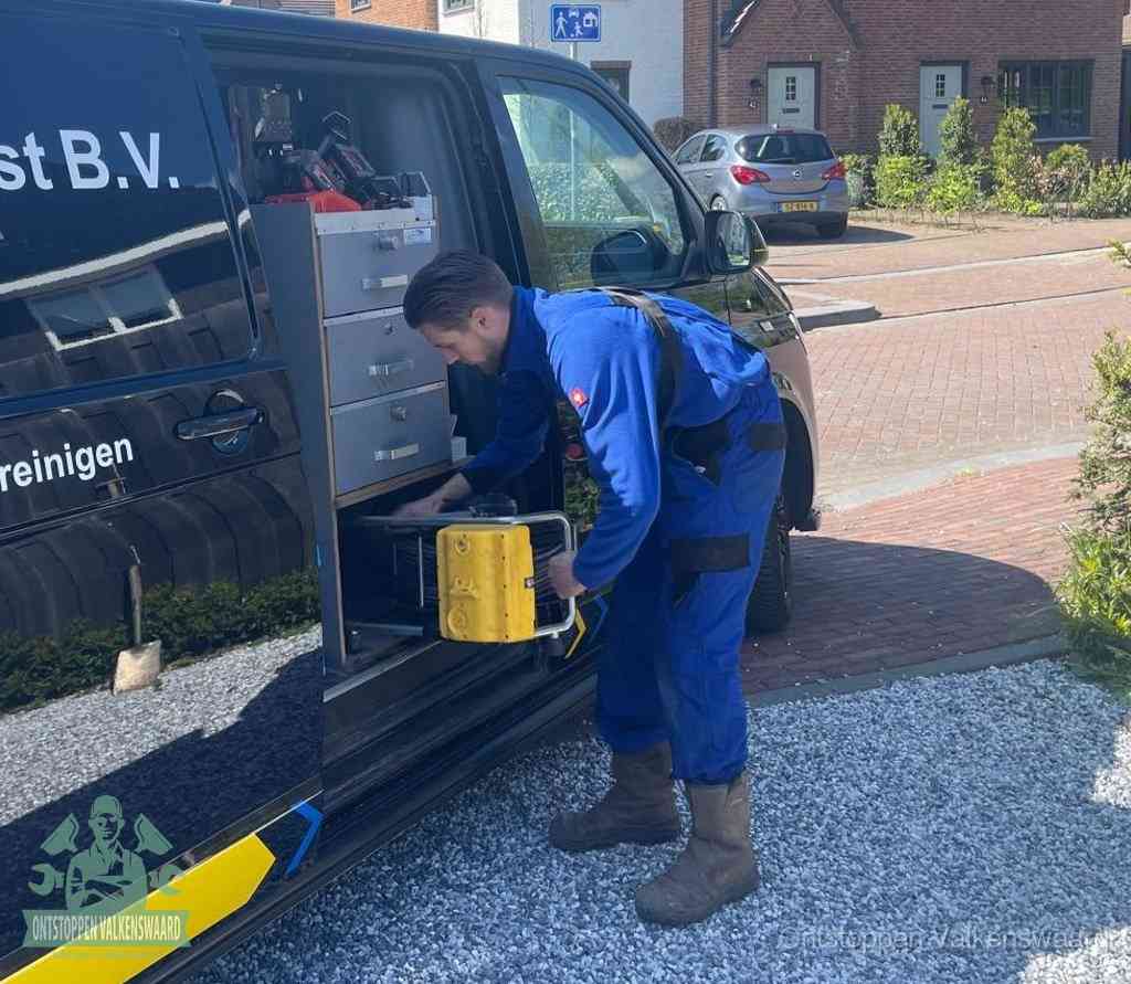 Een monteur pakt buiten op de oprit gereedschap uit de bedrijfsbus, het moment om een professional in te schakelen voor een verstopte afvoer in Valkenswaard