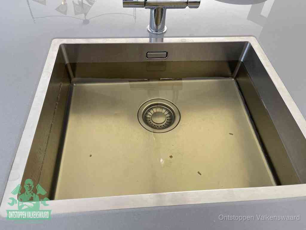Stilstaand water in een rvs spoelbak dat niet wegloopt, een duidelijk signaal van een gootsteenverstopping in Valkenswaard