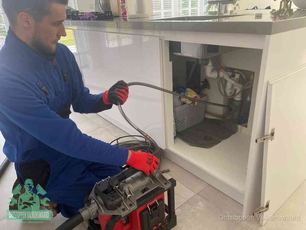 Een monteur reinigt de keukenafvoer grondig met een veermachine om terugkerende gootsteenverstoppingen te voorkomen in Valkenswaard