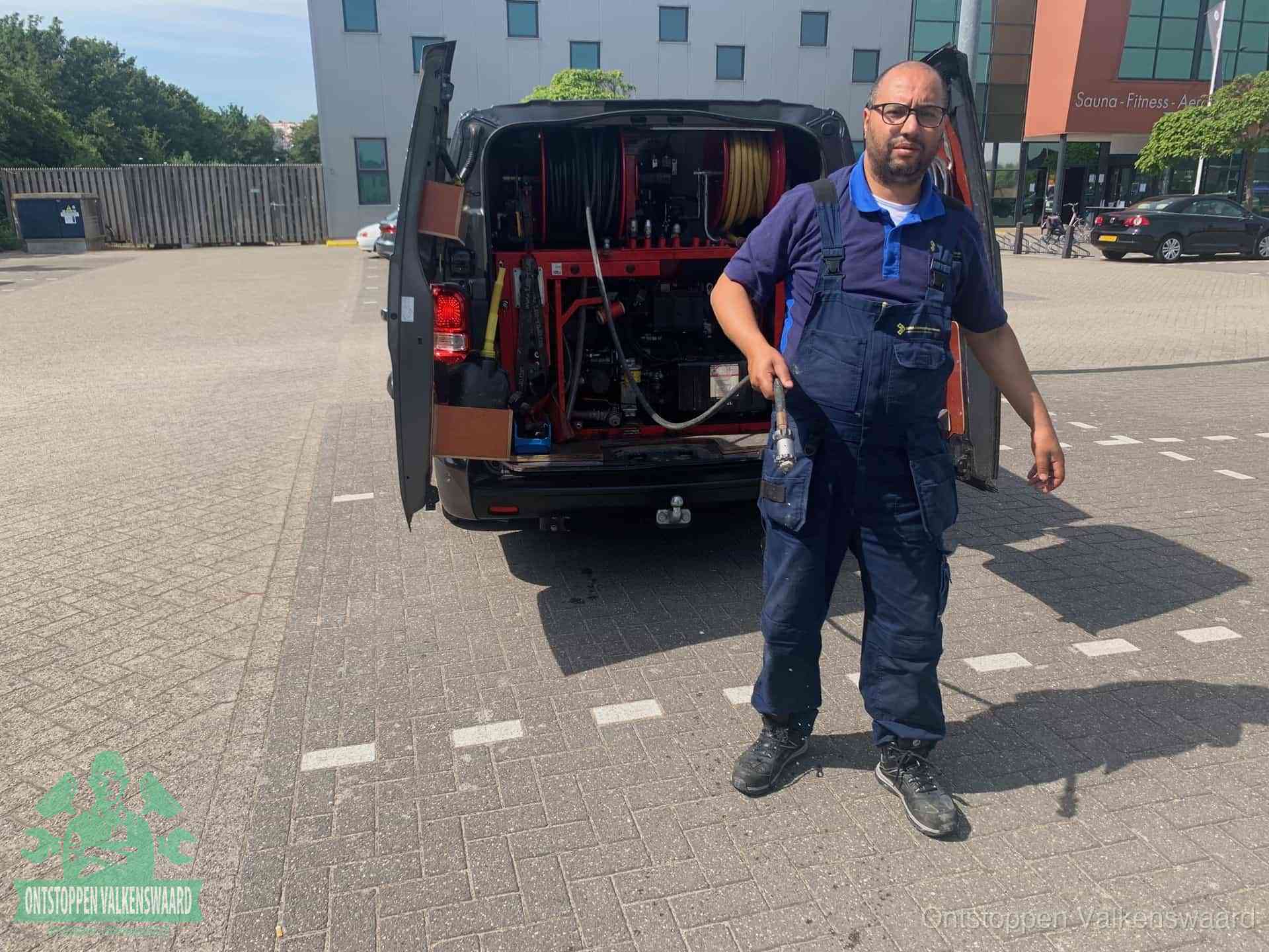 Een monteur bij zijn bestelbus met een hogedruk- en rioolreinigingsunit, klaar om de oorzaak van terugkerende wc-verstoppingen aan te pakken in Valkenswaard