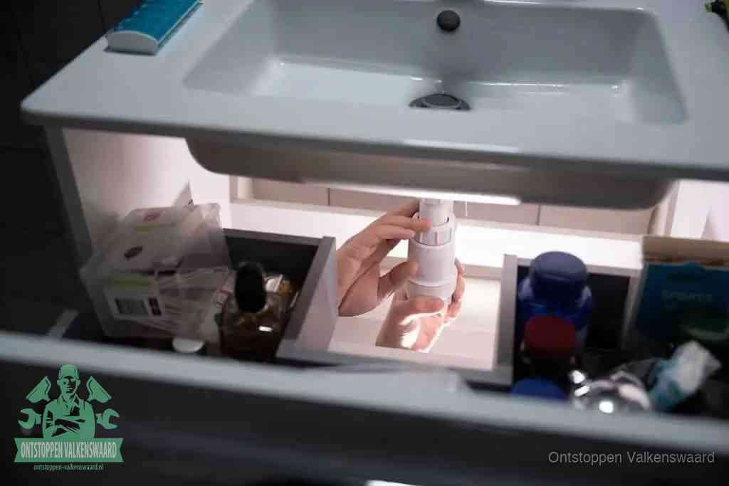 Een pompfles met zeep boven een wastafel in de toiletruimte, de warm water en afwasmiddel-methode om de wc te ontstoppen in Valkenswaard