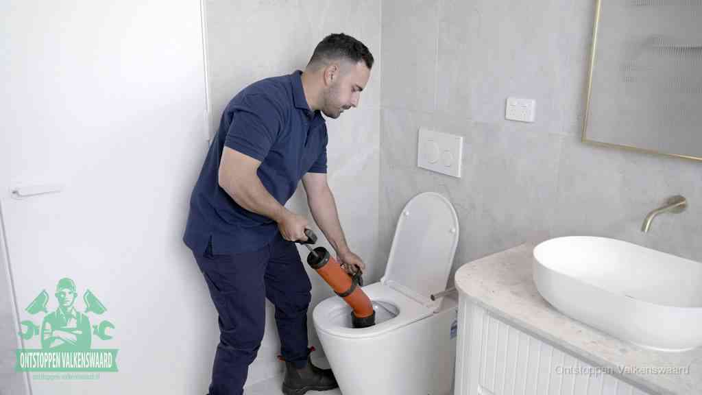 Een monteur gebruikt een handmatige perspomp (toiletontstopper) op een wandcloset tijdens het professioneel wc ontstoppen in Valkenswaard
